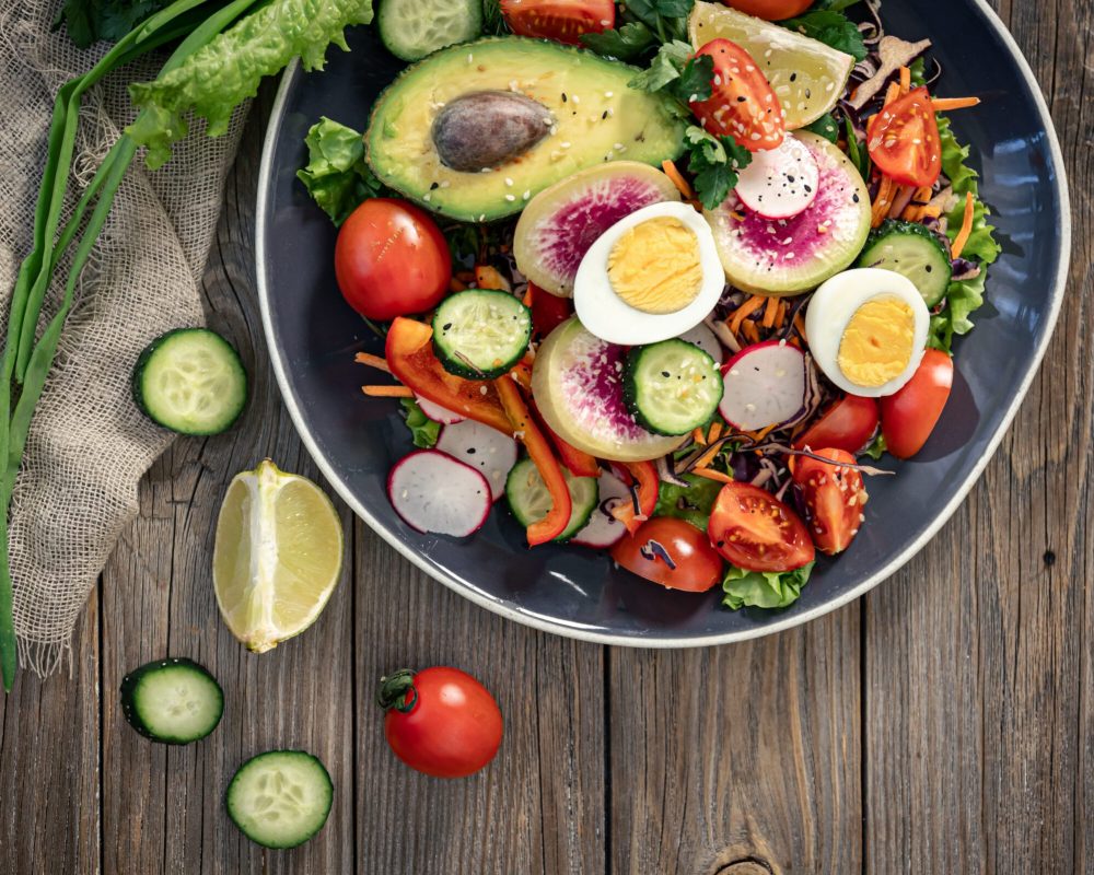 Appetizing vegetable salad with eggs, avocado on a wooden background. нутриціологиня